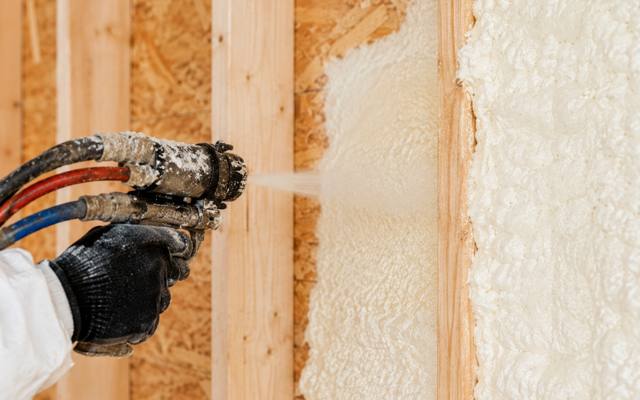 Close up of spray foam expanding out of the gun into a stud bay